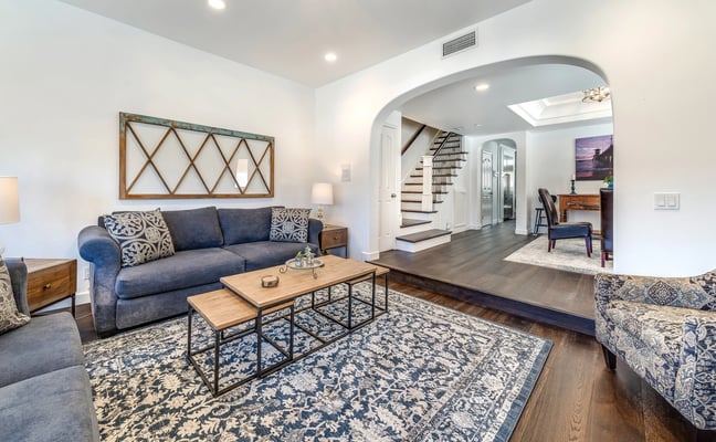 Covered patio with fire table, upholstered seating, metal chairs, and glass doors opening to interior